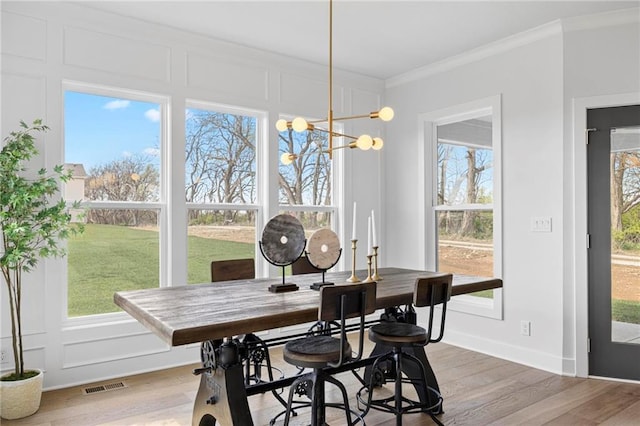 18452 Windsor St, Overland Park, KS 66085 - dining space with light wood-style flooring, visible vents, crown molding, and a wealth of natural light