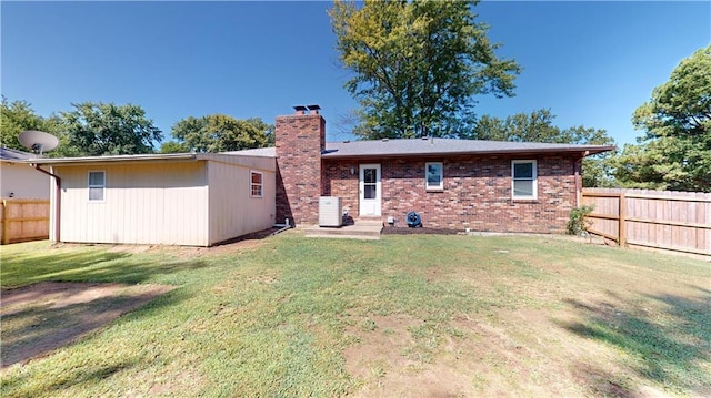 rear view of house featuring a lawn and central air condition unit