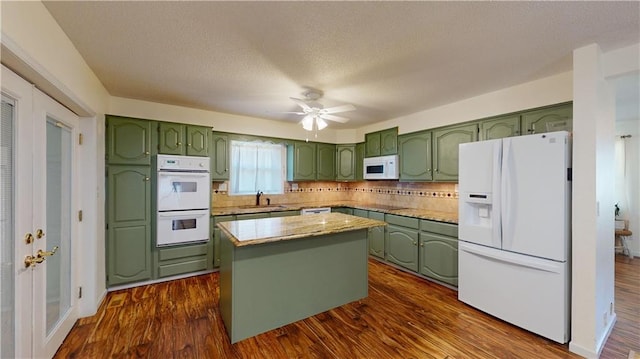 kitchen with white appliances, backsplash, dark hardwood / wood-style flooring, a kitchen island, and sink