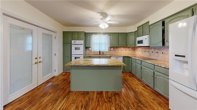 kitchen with white appliances, sink, a center island, dark wood-type flooring, and french doors