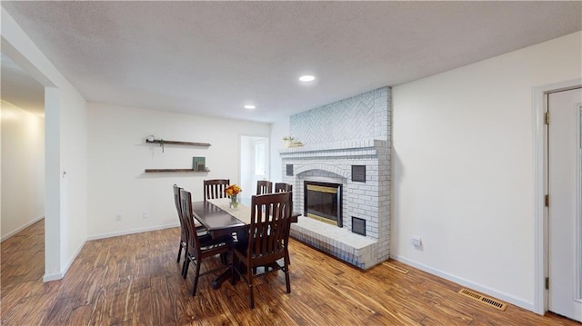 dining space with a brick fireplace and wood-type flooring