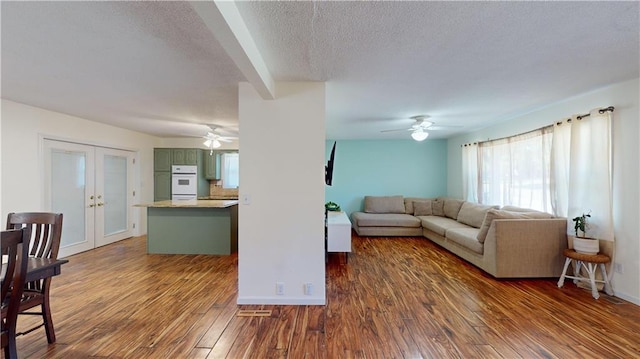 living room featuring ceiling fan, dark hardwood / wood-style floors, french doors, and a textured ceiling