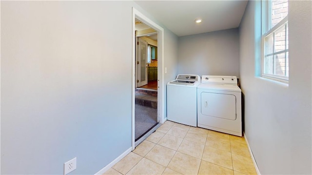 laundry area with washer and clothes dryer and light tile patterned floors