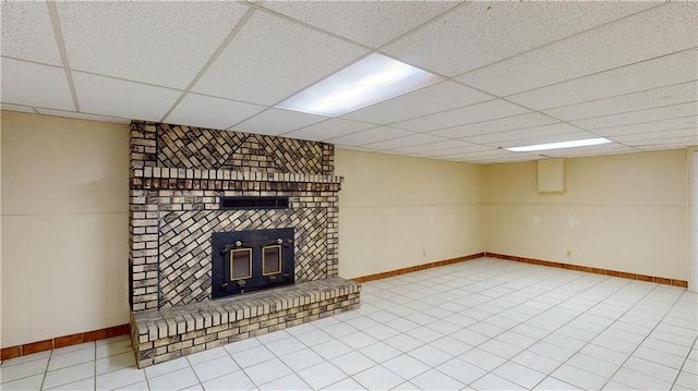 unfurnished living room featuring a fireplace, a drop ceiling, and tile patterned flooring