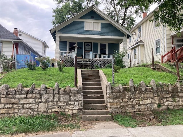 bungalow-style home featuring stairs, a porch, and a front yard