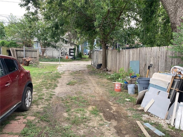 view of yard with dirt driveway and fence