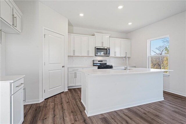 kitchen with a kitchen island with sink, dark wood-type flooring, sink, white cabinetry, and appliances with stainless steel finishes