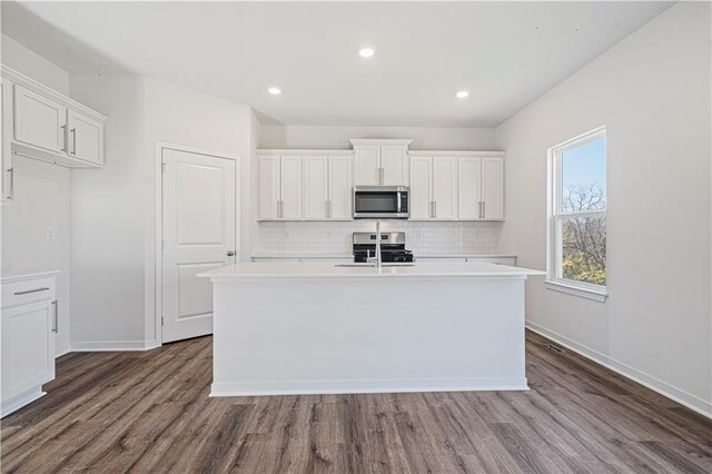 kitchen with a kitchen island with sink, white cabinetry, stainless steel appliances, and dark hardwood / wood-style flooring