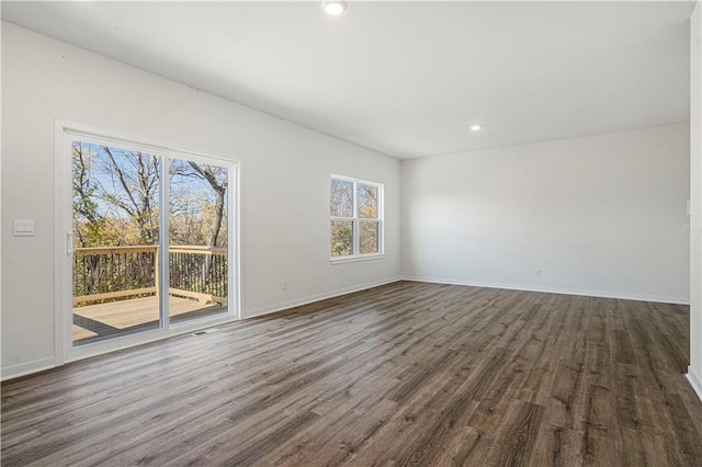 spare room featuring dark wood-type flooring and plenty of natural light