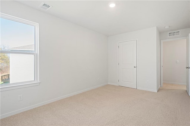 unfurnished bedroom with light colored carpet and a closet