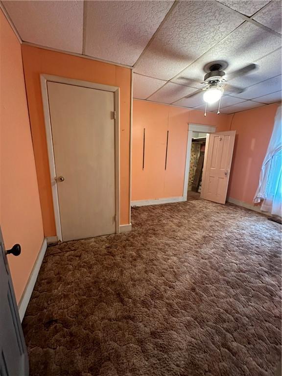 empty room featuring carpet flooring, ceiling fan, and a drop ceiling