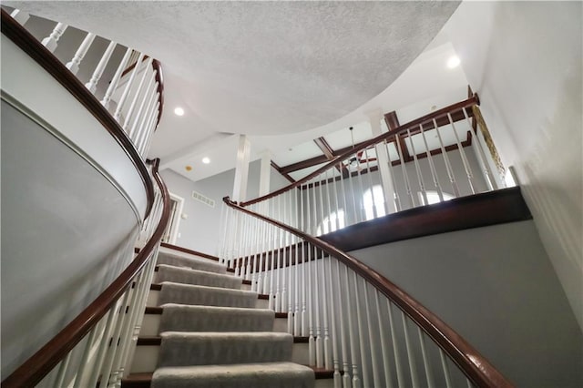 staircase featuring a towering ceiling and a textured ceiling