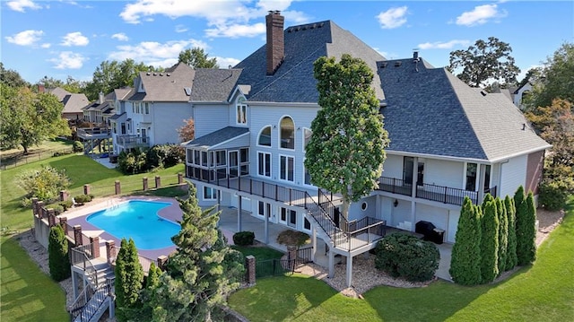 back of house featuring a lawn, a sunroom, a fenced backyard, a chimney, and a patio area