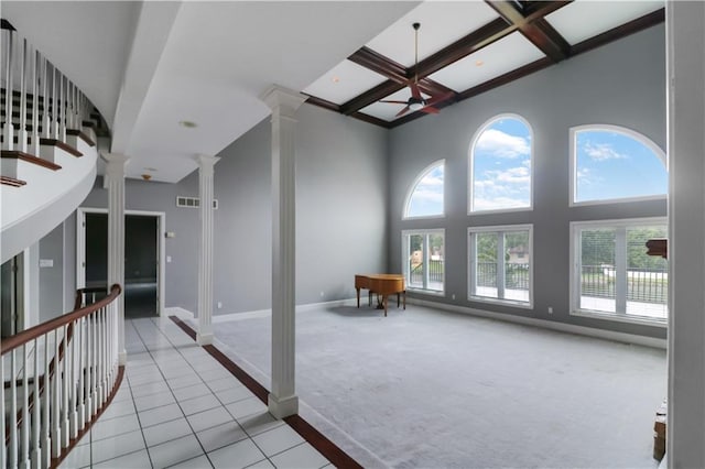 corridor featuring coffered ceiling, beamed ceiling, ornate columns, light colored carpet, and a towering ceiling