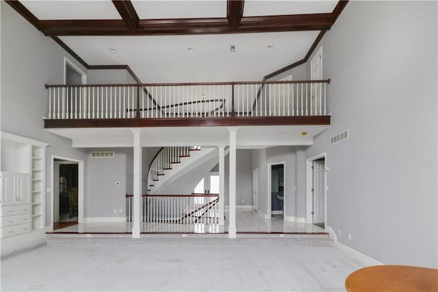 unfurnished living room with built in features, ornate columns, visible vents, a towering ceiling, and baseboards