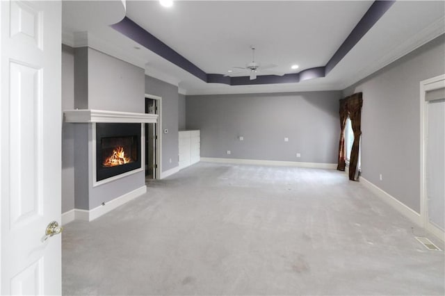 unfurnished living room featuring baseboards, a raised ceiling, a glass covered fireplace, ceiling fan, and carpet flooring