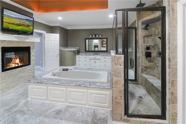 bathroom featuring a stall shower, a glass covered fireplace, crown molding, vanity, and a bath