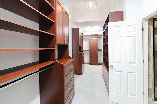 walk in closet featuring an inviting chandelier and light colored carpet