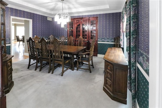 dining space featuring a raised ceiling, ornamental molding, a chandelier, baseboards, and wallpapered walls