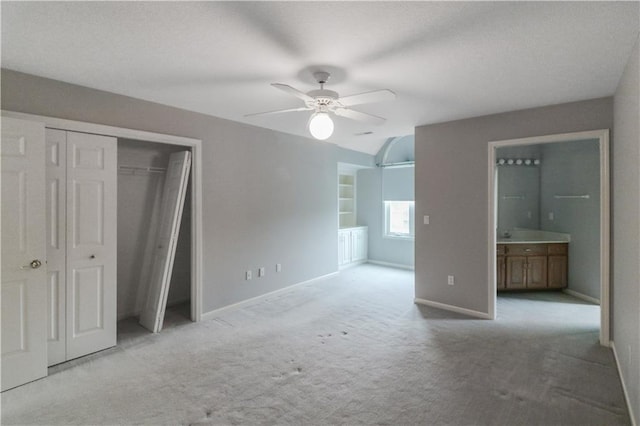 unfurnished bedroom featuring ceiling fan, light colored carpet, and ensuite bathroom