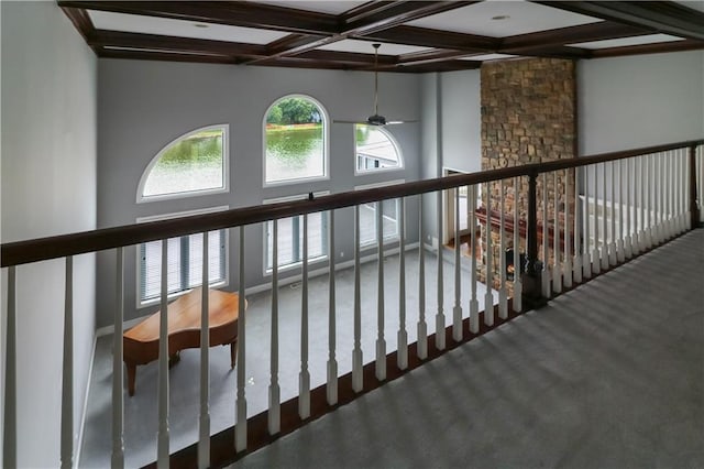 staircase featuring a stone fireplace, carpet, coffered ceiling, and beamed ceiling