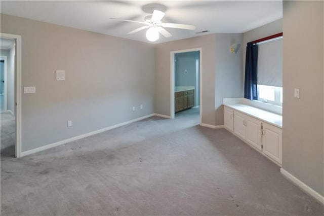 unfurnished bedroom featuring light colored carpet, connected bathroom, and ceiling fan