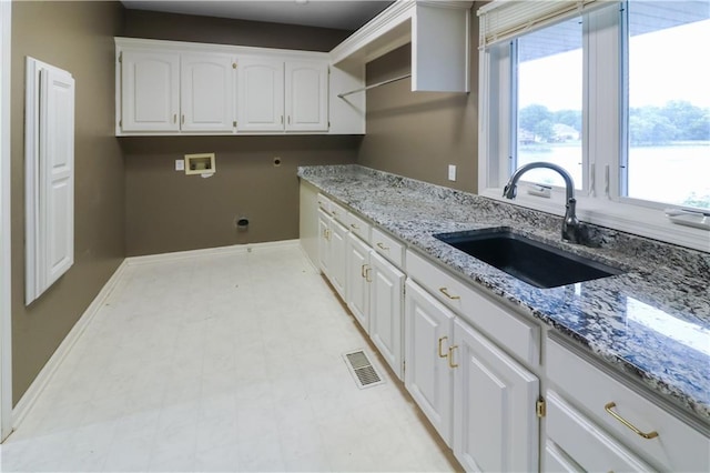 kitchen featuring light stone counters, sink, and white cabinetry