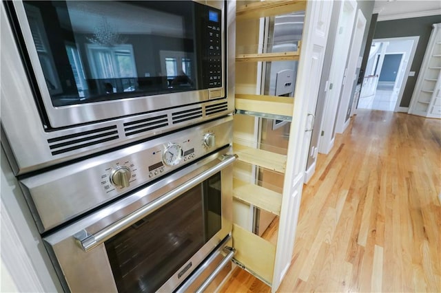 details featuring light wood-type flooring, appliances with stainless steel finishes, and crown molding