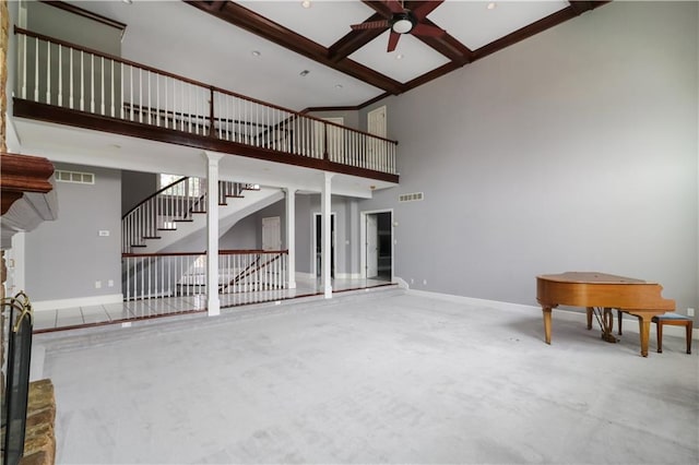 unfurnished living room with coffered ceiling, ceiling fan, beamed ceiling, and a towering ceiling