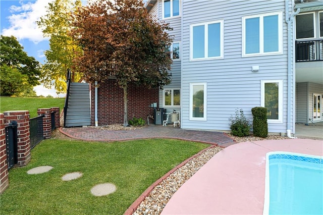 rear view of property with a fenced in pool, a patio area, a yard, and fence