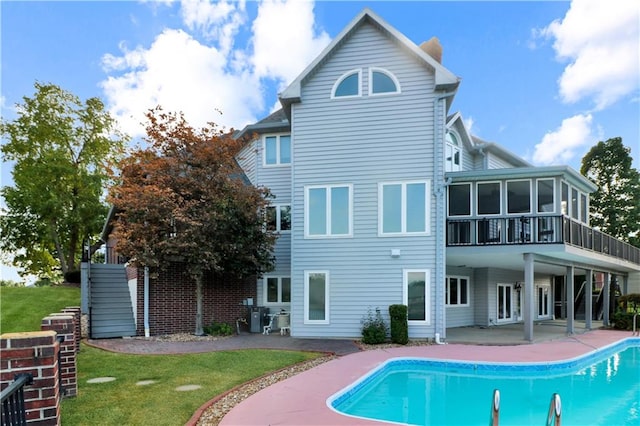 back of property featuring a fenced in pool, a yard, a patio, a sunroom, and stairs