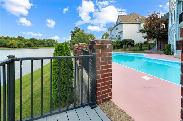 view of swimming pool featuring a water view, fence, and a yard