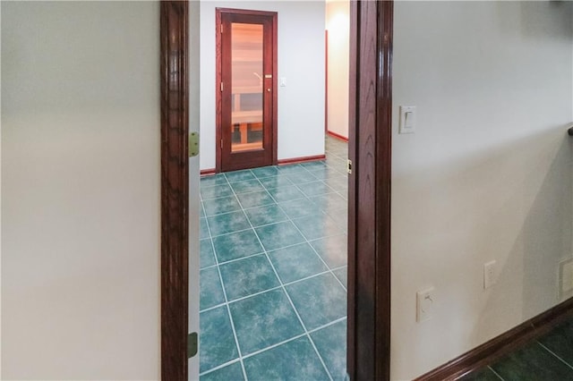 corridor featuring dark tile patterned flooring and baseboards