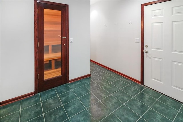 unfurnished room featuring dark tile patterned floors and baseboards