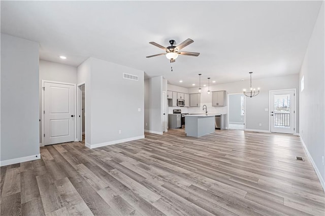 unfurnished living room with sink, light hardwood / wood-style floors, and ceiling fan with notable chandelier