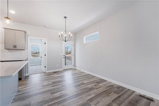 unfurnished dining area featuring plenty of natural light, wood-type flooring, and a notable chandelier