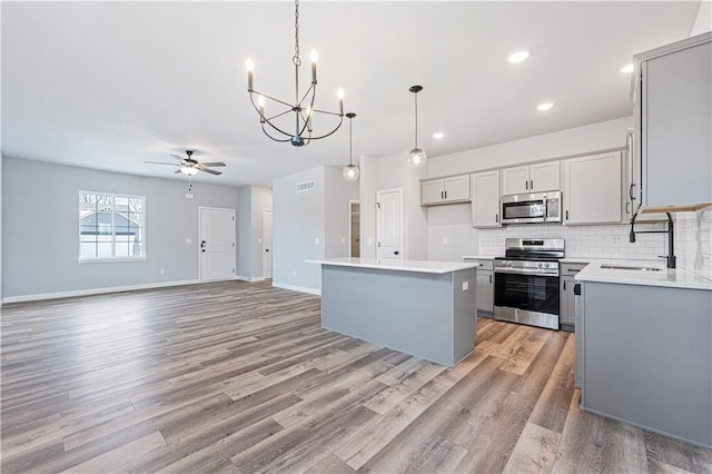 kitchen with stainless steel appliances, a center island, pendant lighting, and gray cabinetry