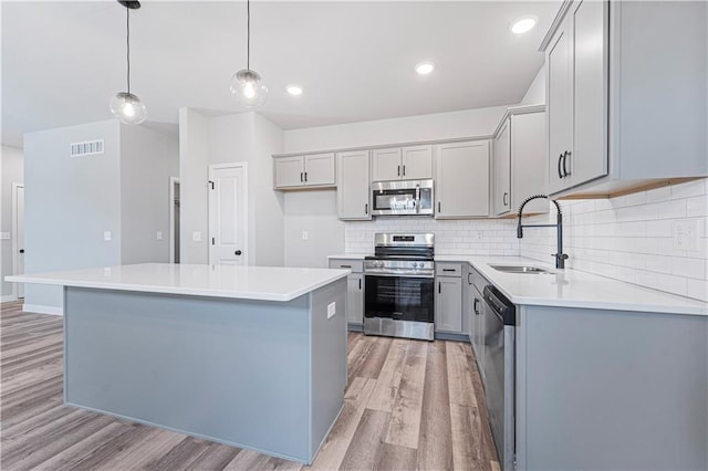 kitchen with stainless steel appliances, a center island, sink, and hanging light fixtures