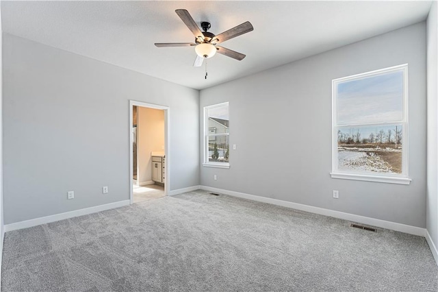 unfurnished bedroom with ensuite bathroom, light colored carpet, and ceiling fan