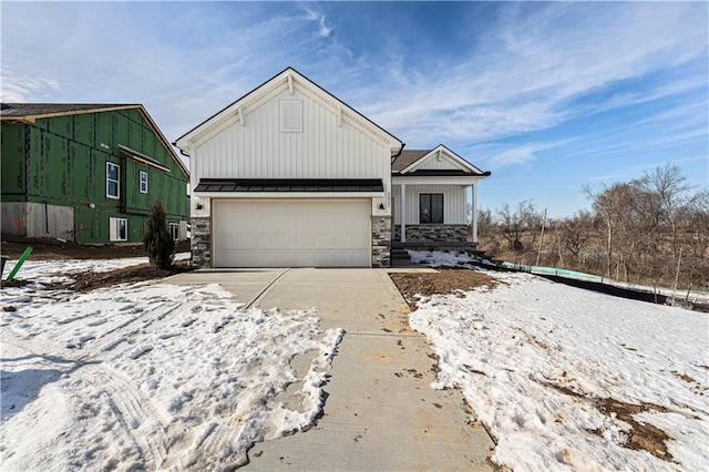 view of front of property featuring concrete driveway, stone siding, metal roof, a standing seam roof, and board and batten siding