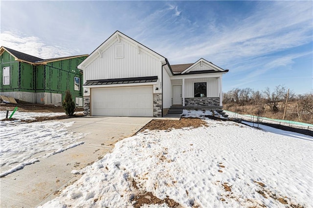 view of front of house featuring a standing seam roof, metal roof, a garage, stone siding, and driveway