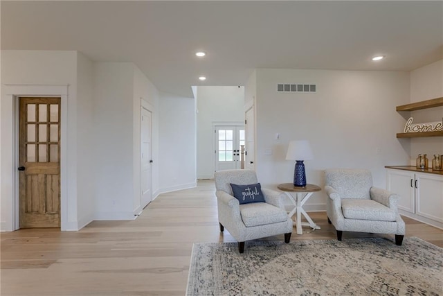 living area with french doors and light hardwood / wood-style flooring