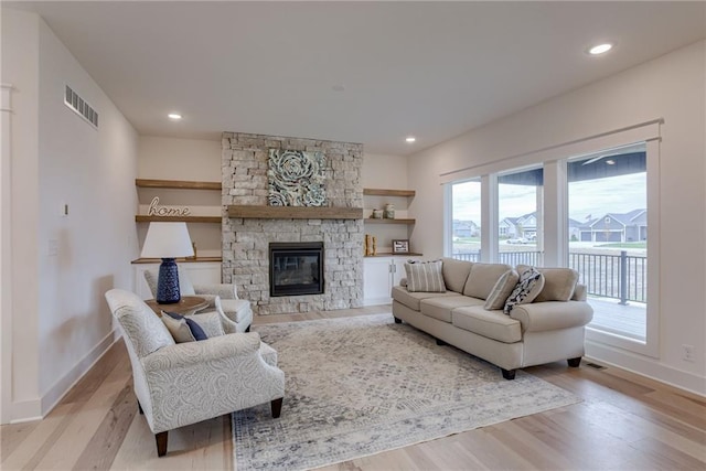 living room featuring a stone fireplace and light hardwood / wood-style flooring