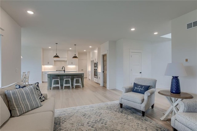 living room with sink and light hardwood / wood-style flooring