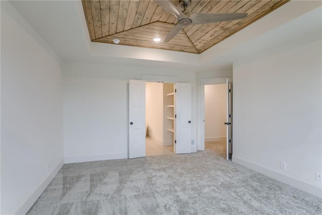 carpeted spare room featuring wood ceiling, ceiling fan, and a tray ceiling