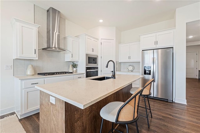 kitchen with appliances with stainless steel finishes, wall chimney exhaust hood, white cabinets, and dark wood-type flooring