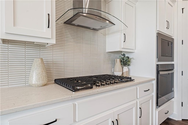 kitchen with light stone countertops, stainless steel appliances, tasteful backsplash, and ventilation hood