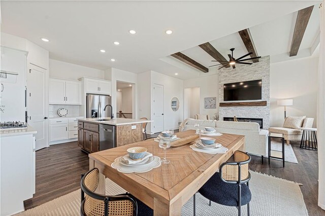 1602 NW 104th Ter, Kansas City, MO 64155 - dining space with a ceiling fan, a stone fireplace, beam ceiling, and dark wood-type flooring