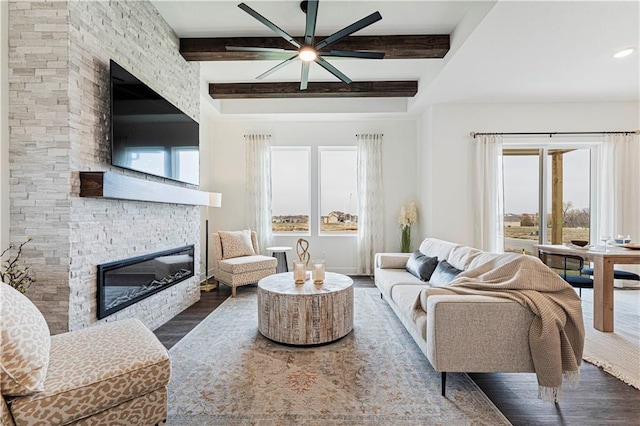 living room featuring hardwood / wood-style flooring, beamed ceiling, a fireplace, and ceiling fan