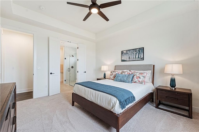 carpeted bedroom featuring a raised ceiling and ceiling fan